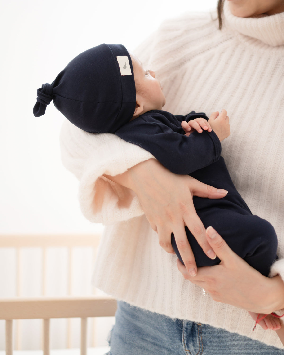 Mamá cargando a su recién nacido con conjunto azul marino y gorrito