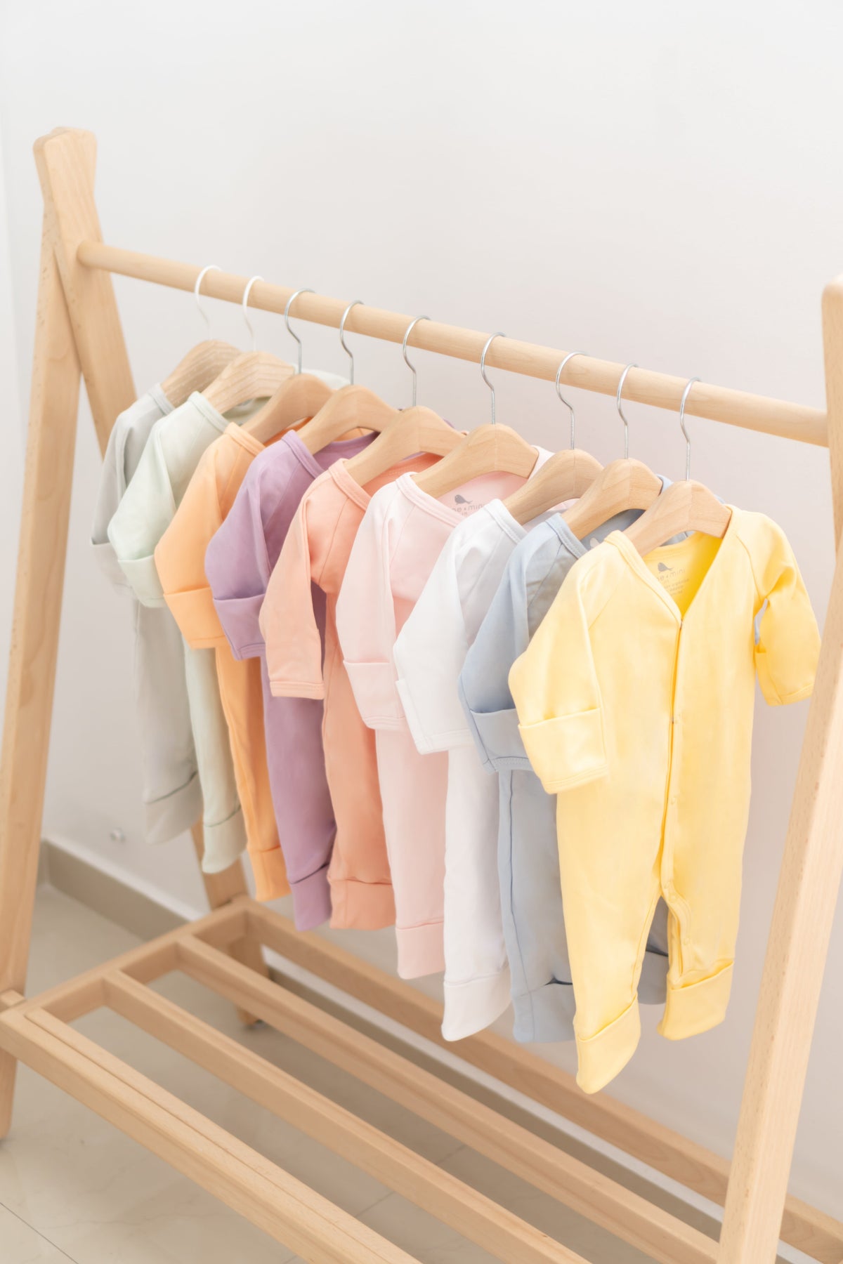 Ropero de bebé armado: pijamas y bodies en colores pastel en su rack